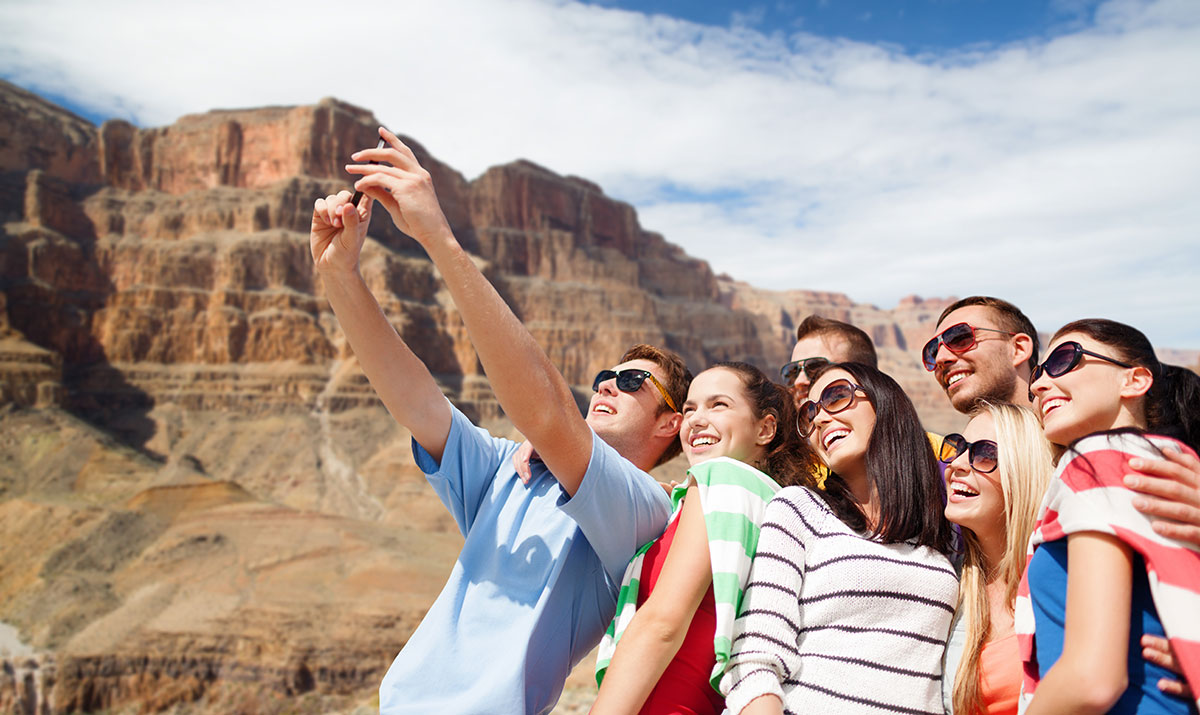 travel group smiling taking selfie at mountain range landmark